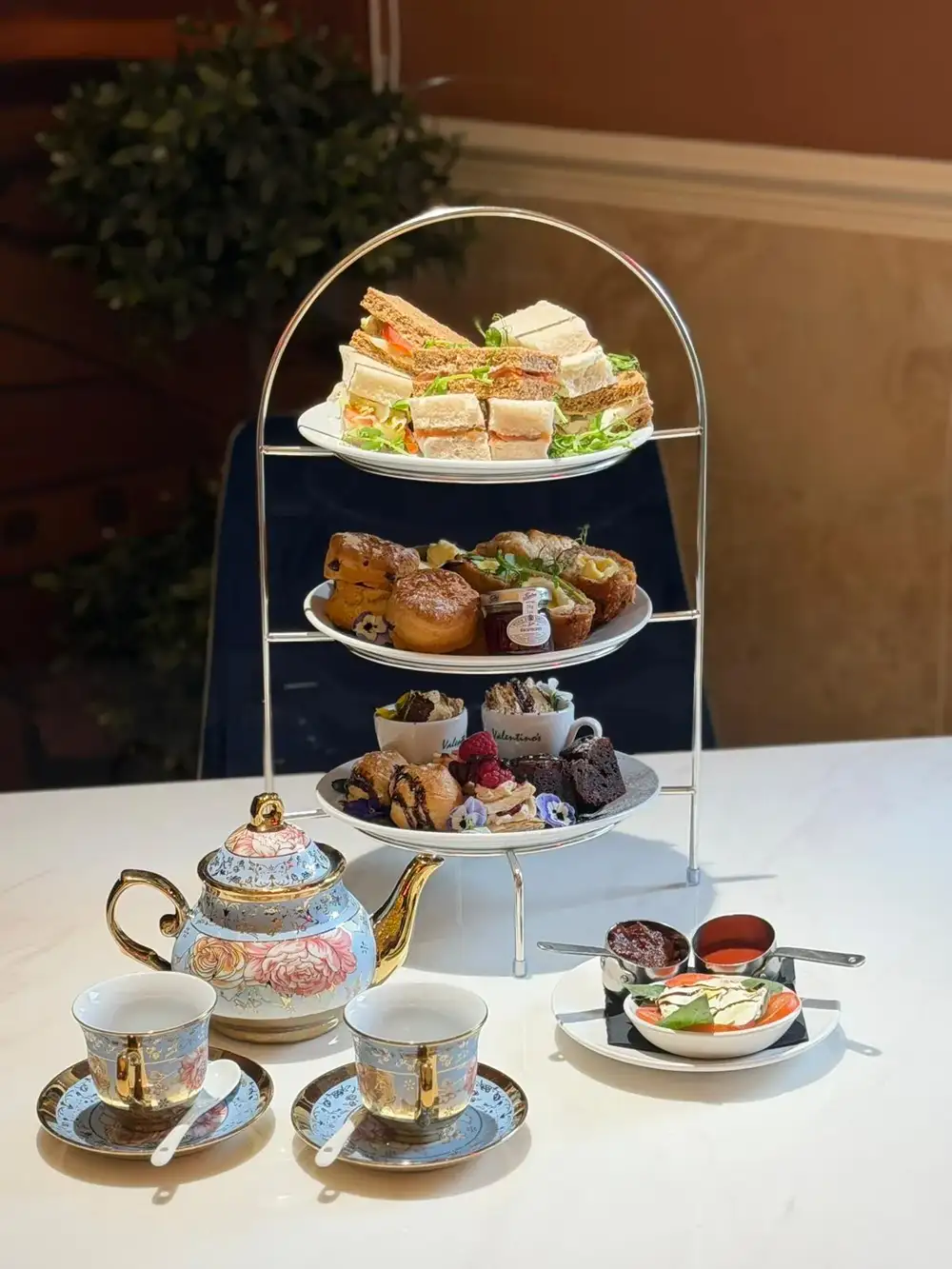 Valentino's Afternoon Tea Valentino's Afternoon Tea — a tiered stand of finger sandwiches, scones, sweet treats and a floral teapot
